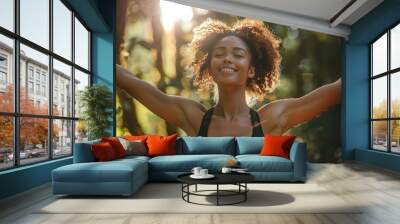 A woman with curly hair is smiling and looking up at the sun. Concept of happiness and positivity Wall mural