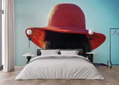 A woman wearing a vibrant red hat, viewed from behind against a clear blue sky. Wall mural