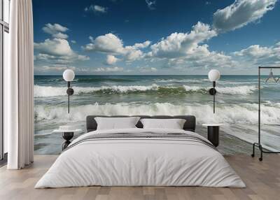 Seascape with foamy waves crashing on sandy beach under blue sky with white clouds Wall mural