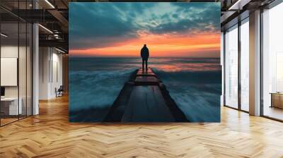 Silhouette of man standing on pier at sunset with ocean in background Wall mural