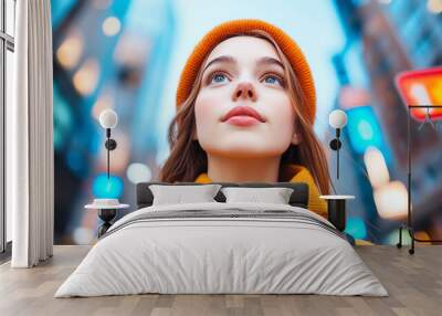 Young woman in an orange hat looking up in a colorful urban environment. Wall mural