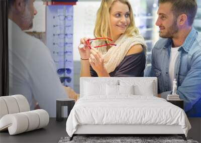 Woman in optical center trying eyeglasses on Wall mural