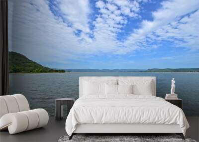 White clouds in blue sky and smooth waves in the water Wall mural