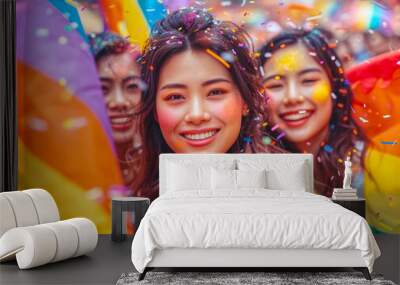 Three asian woman wearing jackets in a vibrant, Pride day festive atmosphere. with celebrate amidst flying confetti and rainbow flags, symbolizing LGBTQ+ Wall mural