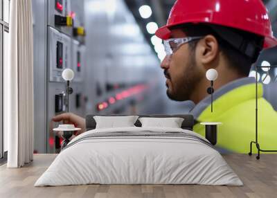 A worker in safety gear operates control panel machinery in an industrial setting, showcasing a focus on precision and safety in operations. Wall mural