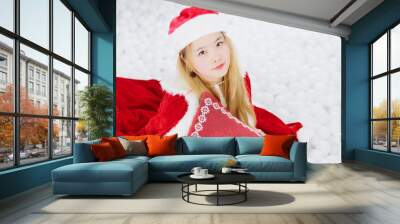 Christmas Santa. Beautiful smiling woman model. Makeup. Healthy long curly yellow hair style. Elegant lady in red cloak and santa claus hat. happy new year and merry Christmas concept. Wall mural