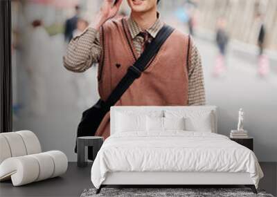 Portrait of a handsome Chinese young man with Korean style clothes walking on street and talking in mobile phone with Shanghai Nanjing road background, male fashion, cool Asian young man lifestyle. Wall mural