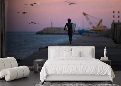 surfer running along pier just after sunset with port and ocean in background Wall mural