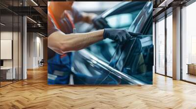 Male auto specialist worker hand rolling car window film on front windscreen glass surface. Car side window film removal and tinting installation. Wall mural