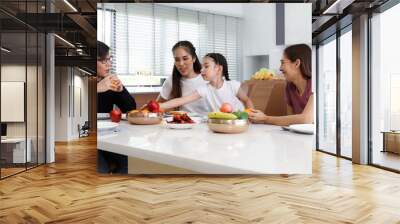 A large, happy Asian family spends their time dining at the tables inside the house. Little daughter having fun chatting Wall mural