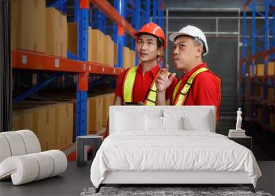 Asian male foreman and worker wearing hard hats Use a tablet to check inventory. Wall mural