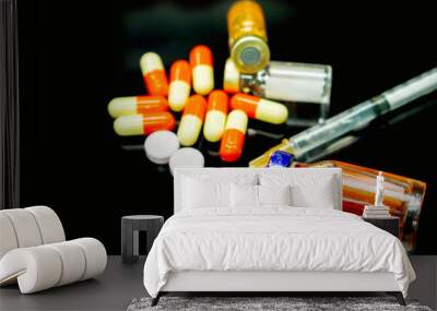 Vaccines in vial, capsules and white pill medicines with a plastic syringe on black background. Wall mural