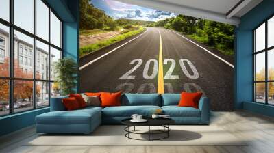 The word 2020 written on highway road in the middle of empty asphalt road at golden sunset and beautiful blue sky. Concept for new year 2020. Wall mural