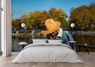 A beautiful girl in a hat walks in an autumn park with coffee Wall mural