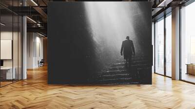 A solitary figure ascends a dark staircase as a beam of light breaks through the rain Wall mural