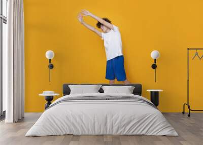 A teenager in a sports uniform is doing a warm-up on a yellow background Wall mural