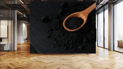 Activated charcoal powder in a wooden spoon on a dark background Wall mural