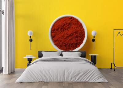 Bowl with red pepper powder on yellow, top view Wall mural