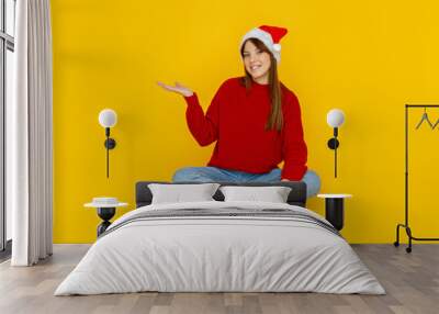 Concept of people, girl in santa hat on yellow background Wall mural