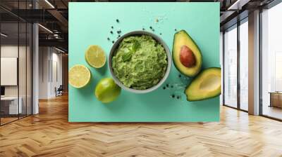 Concept of tasty eating with bowl of guacamole on mint background Wall mural