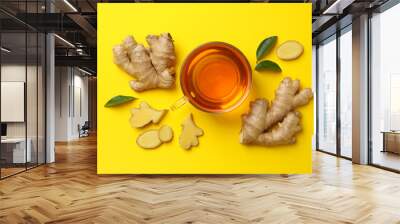 Fresh ginger and cup of tea on yellow background Wall mural