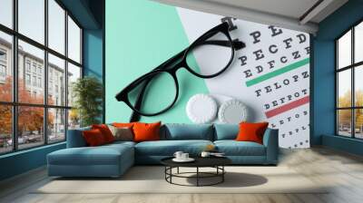 Glasses, case for contact lenses and eye test chart on mint background, top view Wall mural