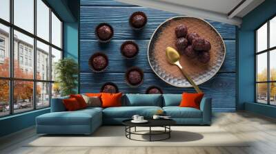 Golden spoon and brigadeiro in plate and on blue wooden background, top view Wall mural