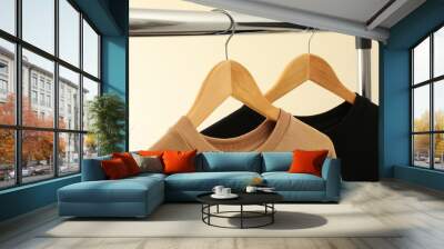 Hangers with stylish sweatshirts on beige background Wall mural