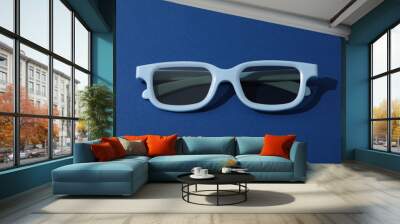 Light blue glasses with tinted lenses on dark blue background Wall mural