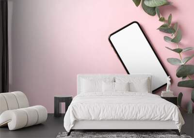 Phone with empty screen and plant on pink background, top view Wall mural