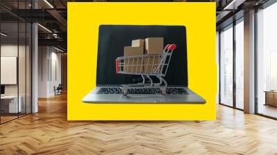 Shopping cart figurine with cardboard boxes on laptop on yellow background with space for text, created with Generative AI technology Wall mural