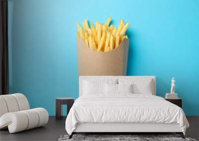 Slices of hot french fries in box on blue background, space for text. Top view Wall mural