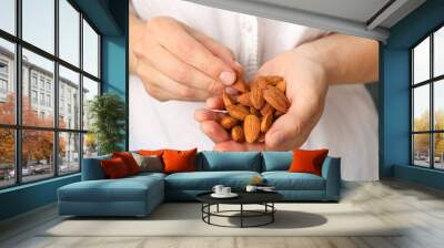 Woman holds tasty almond, close up. Healthy eating Wall mural