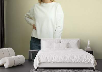 Young woman in white sweatshirt against beige background Wall mural