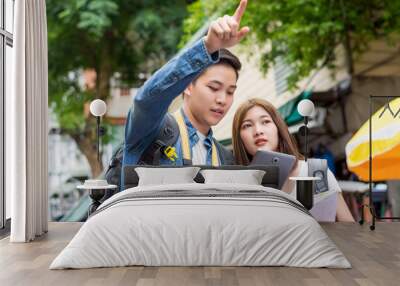 Asian couple tourist using tablet to find location while traveling in Bangkok Wall mural