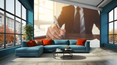 Businessman signing contract document at the table in the office Wall mural