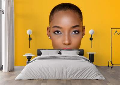 Close up beauty portrait of young African American woman looking at camera in isolated studio yellow background Wall mural