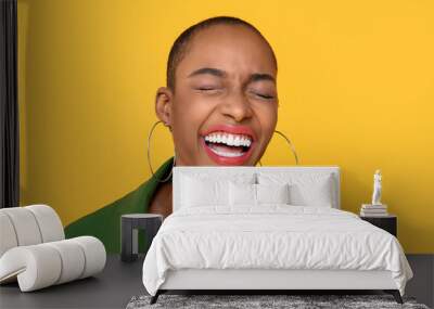 Close up portrait of happy  African American woman laughing with eyes closed in isolated studio yellow background Wall mural