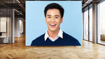 Close up portrait of young handsome smiling Asian man face on light blue studio background Wall mural