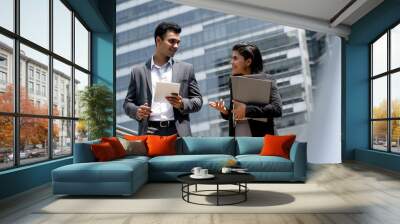 Handsome young Indian businessman in formal suit talking with businesswoman outdoors in the city Wall mural