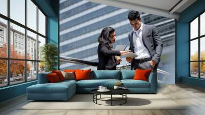 Indian businessman in corporate wear meeting with businesswoman outdoors in the city with office buildings in background Wall mural