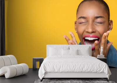 Panoramic close up portrait of ecstatic young African American woman screaming with hands covering face isolated studio yellow background Wall mural