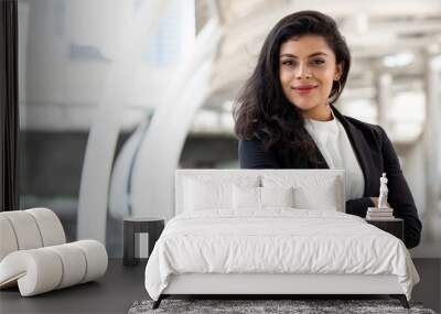 Powerful hispanic woman in business suit standing with arm crossed ourdoors in the city Wall mural