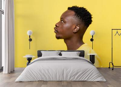 Side view shot of young African man face on isolated yellow studio background Wall mural