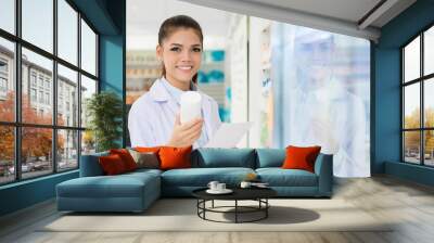 Smiling Asian female pharmacist working in chemist shop or pharmacy Wall mural