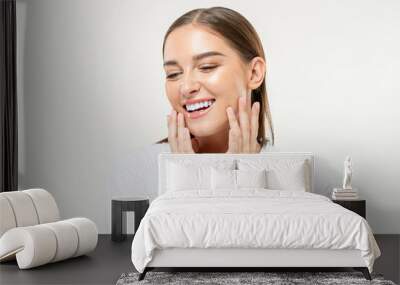 Smiling beautiful Caucasian woman touching her face on isolated studio white background for beauty and skin care concepts Wall mural