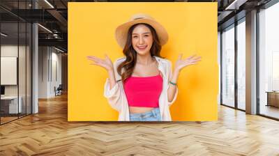 Waist up portrait of smiling pretty Asian woman in summer outfit with open hand gesture in colorful yellow isolated background studio shot Wall mural