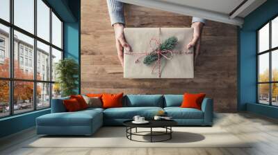 Woman giving a christsmas gift wrapped in brown paper Wall mural