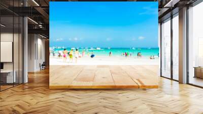 Wood table top on blurred beach background with people in colorful clothes Wall mural