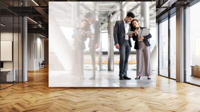 Young Indian businessman with female co-worker looking at mobile phone together outdoors in the city Wall mural